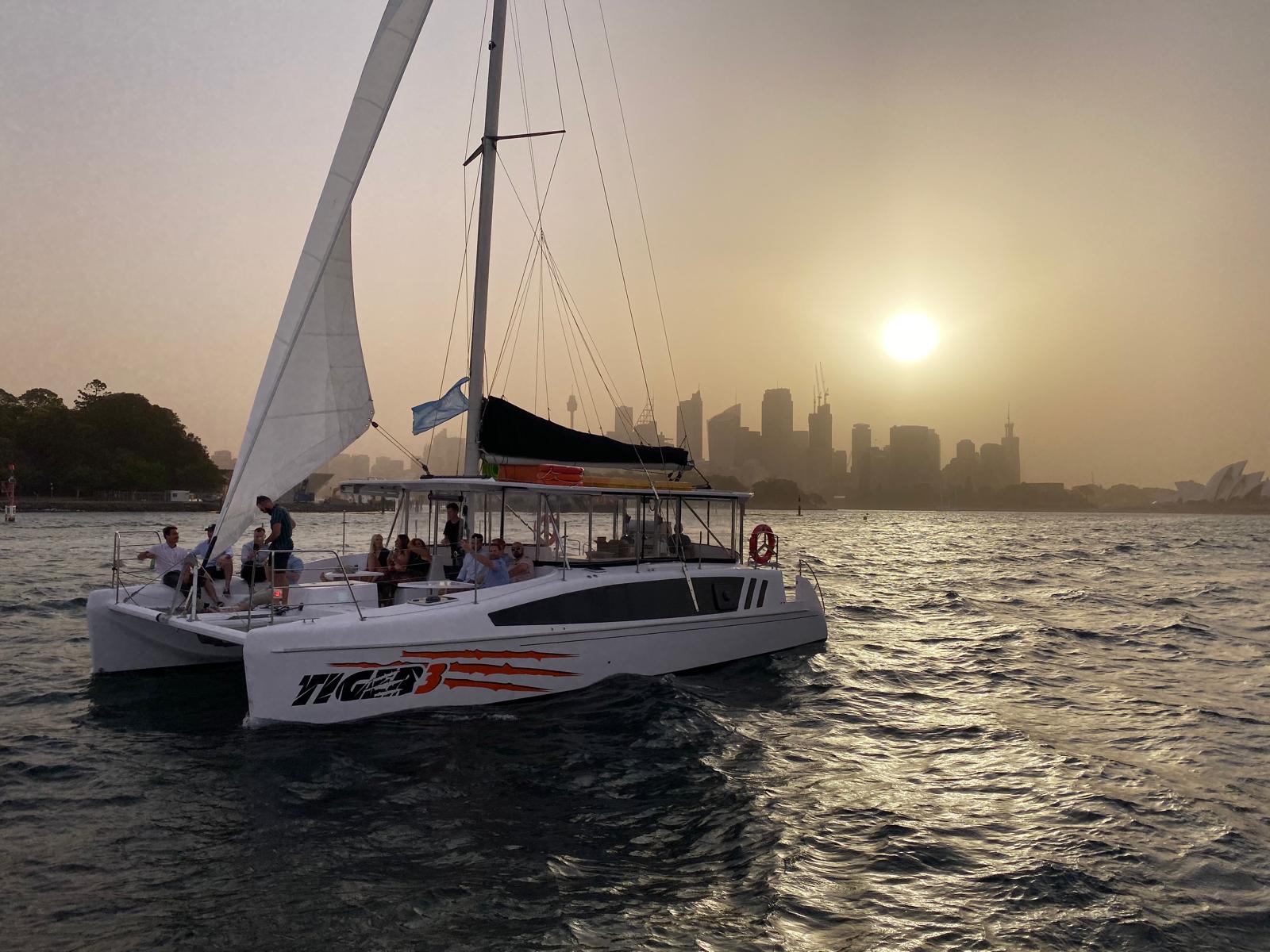 Tiger 3 catamaran with guests onboard at sunset on Sydney Harbour